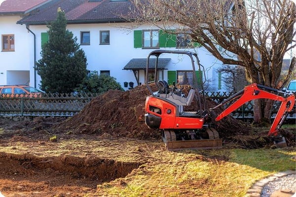 Ein Bagger, der in einem Garten steht und dazu genutzt wird, ein Loch auszuheben