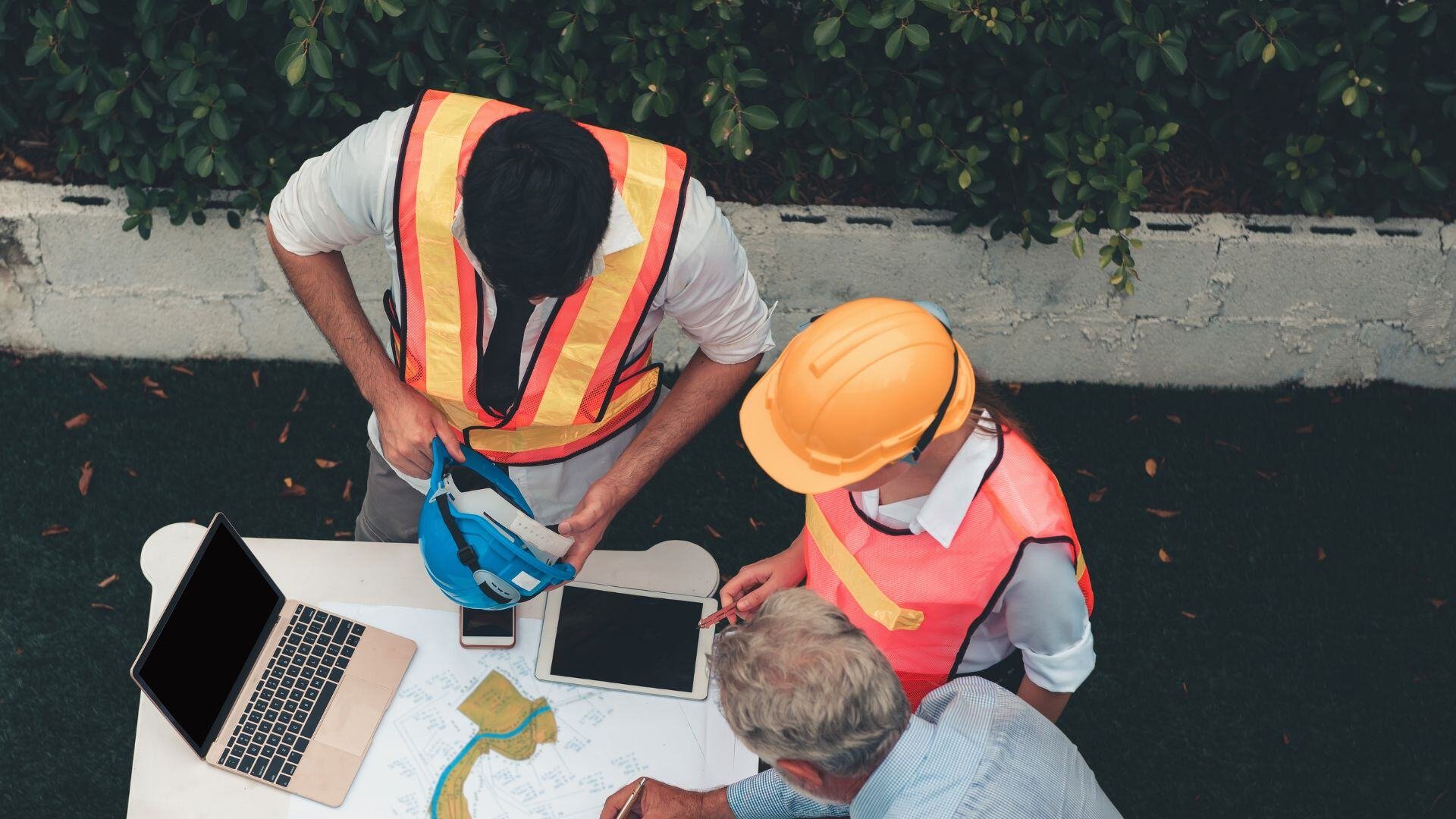 Drei Mitarbeiter auf einer Baustelle bei der Projektplanung